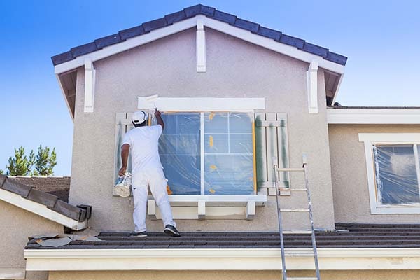 man painting home exterior