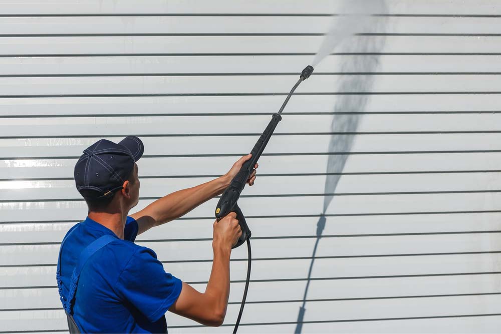 a contractor cleaning the siding of a house with a power washer