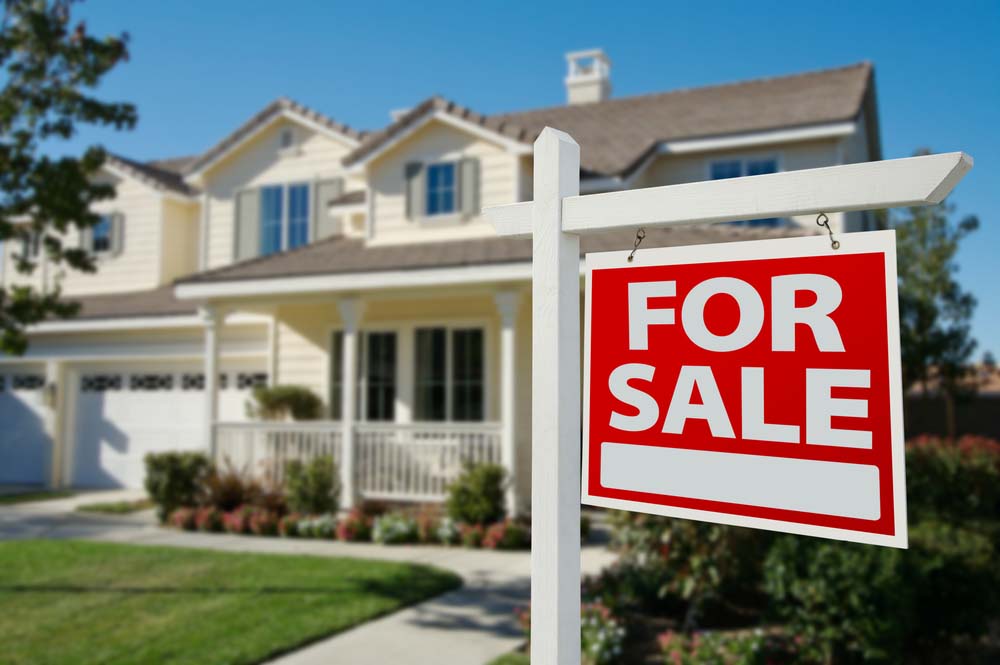 a for sale sign in front of a home with siding