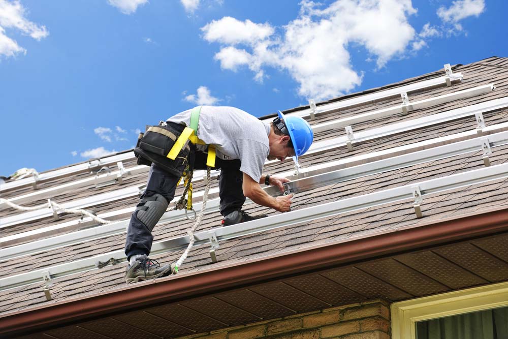 a roofer on a roof installing rails for solar panels