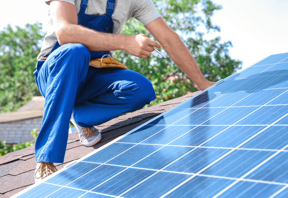 a contractor working on repairing a solar panel on a residential roof