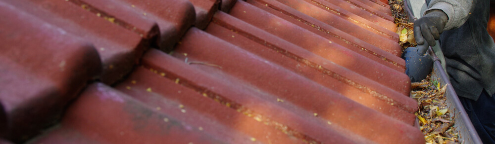 man cleaning tile roof and gutters