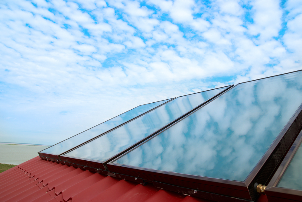 solar panels on a red tile roof under a cloudy sky