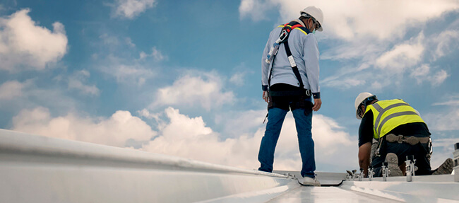 men working on commercial roof with protective gear