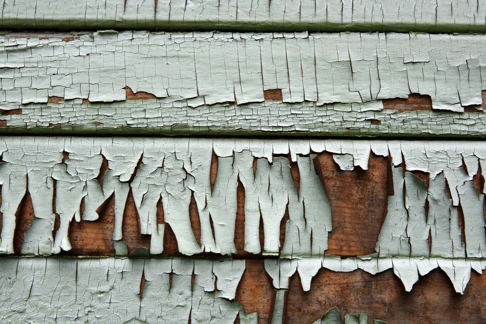 a wooden house with paint peeling off the siding due to water damage