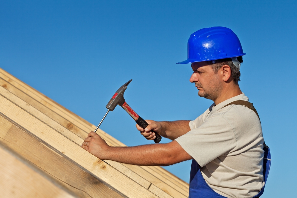 a carpenter working on the roof deck of a roof to replace it